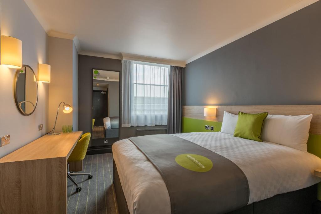 una camera d'albergo con un grande letto e una scrivania di Thistle Express London Luton a Luton