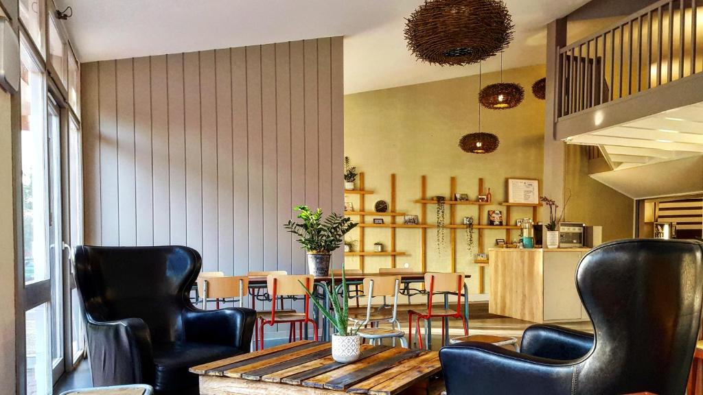 ein Restaurant mit schwarzen Stühlen, einem Tisch, einem Tisch und Stühlen in der Unterkunft HALT HOTEL - Choisissez l'Hôtellerie Indépendante in Lattes