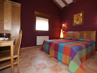 1 dormitorio con cama de arco iris y escritorio en Hosteria San Emeterio en Isla