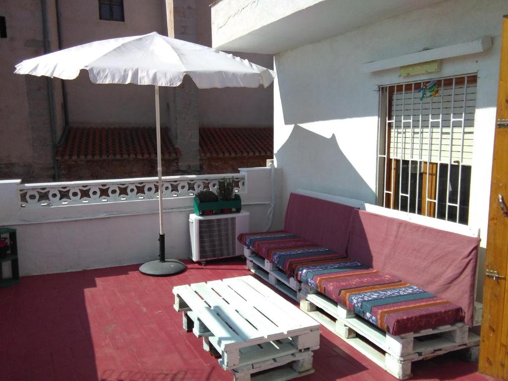 une terrasse avec un banc et un parasol dans l'établissement Casa Serra de Irta, à Santa Magdalena de Pulpis