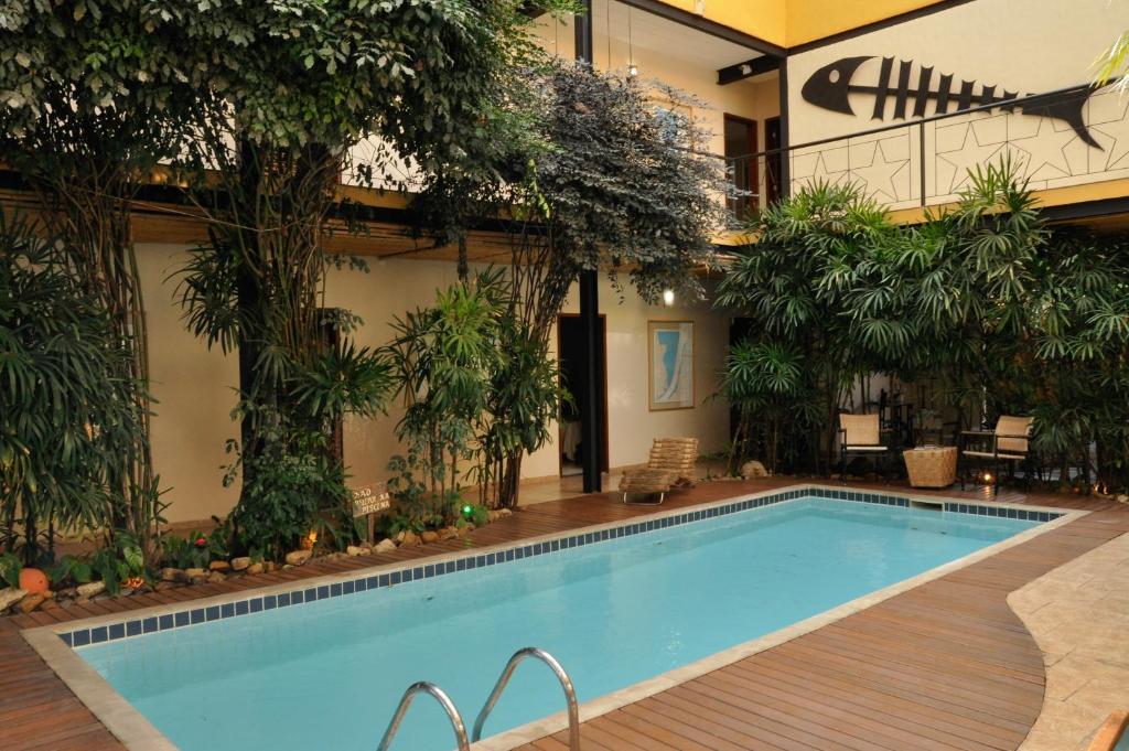 a swimming pool with trees and a building at Pousada Ilha Brazil in Ilhabela