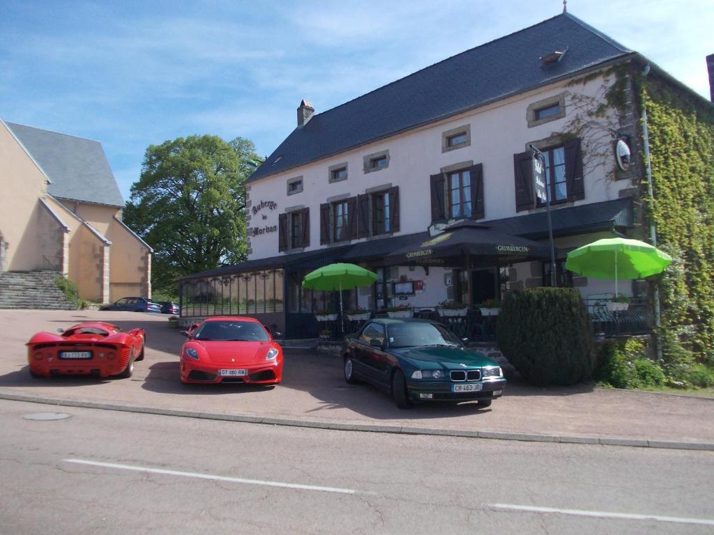 Alligny-en-Morvan的住宿－Auberge du Morvan，三辆汽车停在一座配有绿色遮阳伞的建筑前