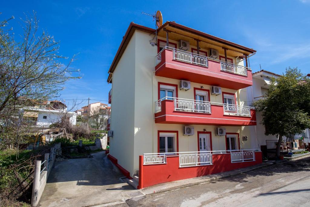 a red and white building with balconies at Grande Apartments in Limenaria