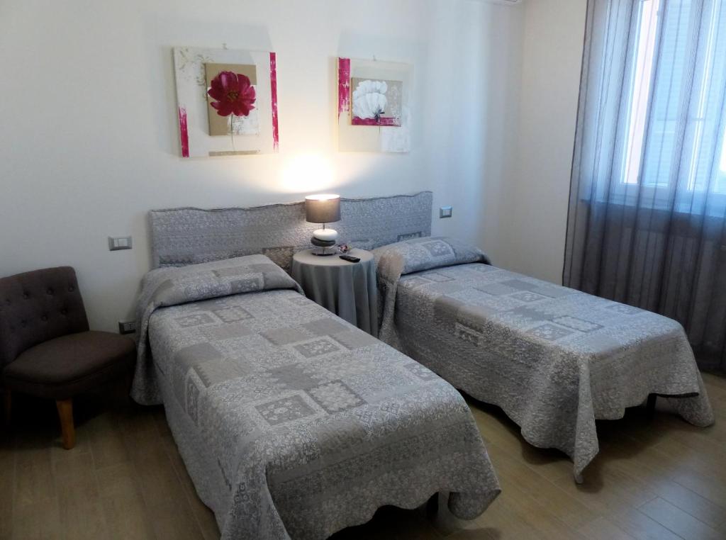 una camera con due letti e un tavolo con una lampada di Marinella Guest House a Cornale