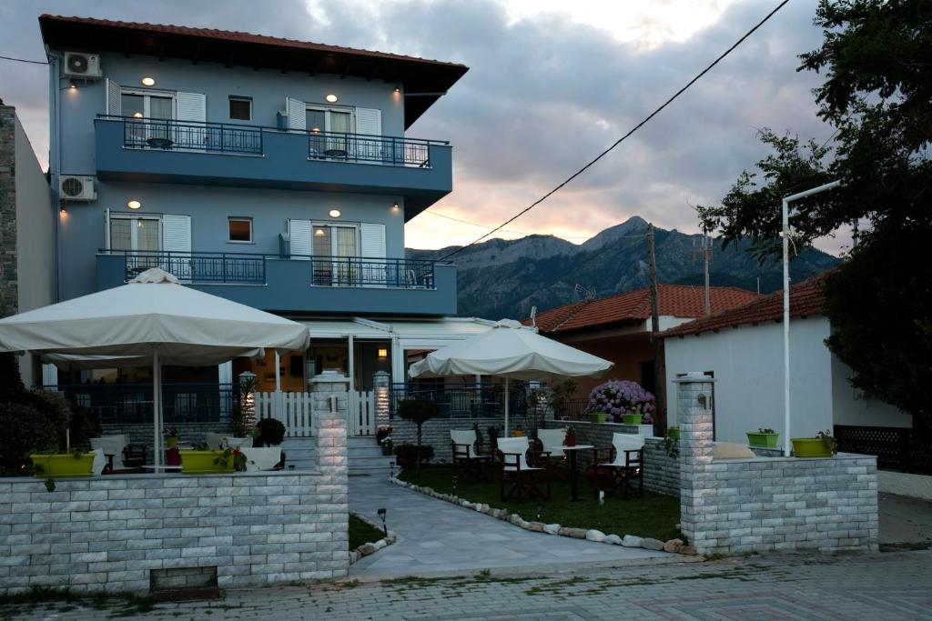 a building with tables and umbrellas in front of it at Arion Hotel in Skala Potamias