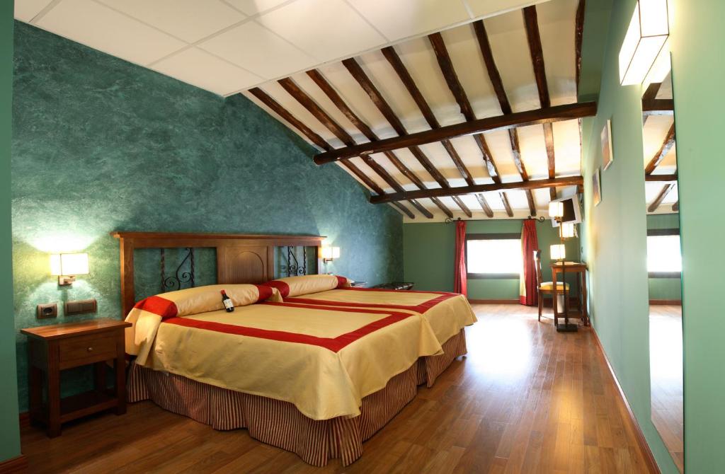 a bedroom with a large bed in a room with green walls at Hotel Duques de Najera in Nájera