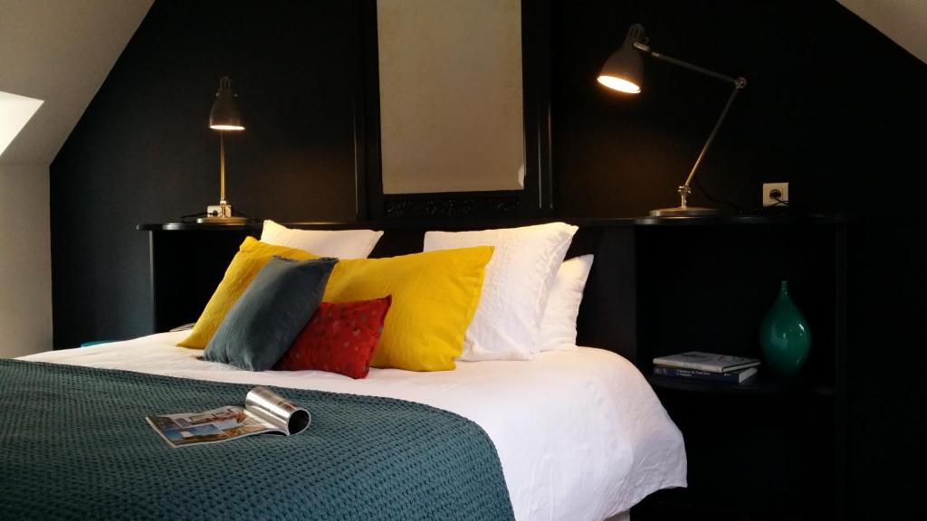 1 dormitorio con 1 cama grande y almohadas coloridas en Le 29 d'à côté, en Pont-Croix