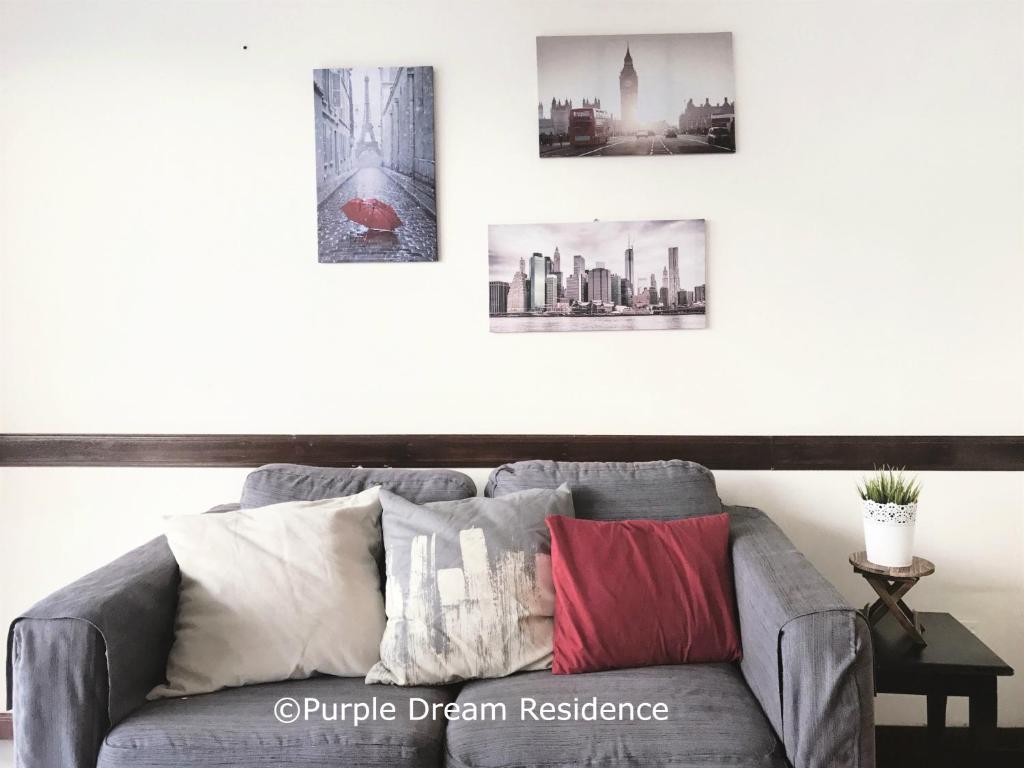un sofá gris en una sala de estar con fotos en la pared en AFamosa Purple Dream Residence Condotel homestay en Melaka
