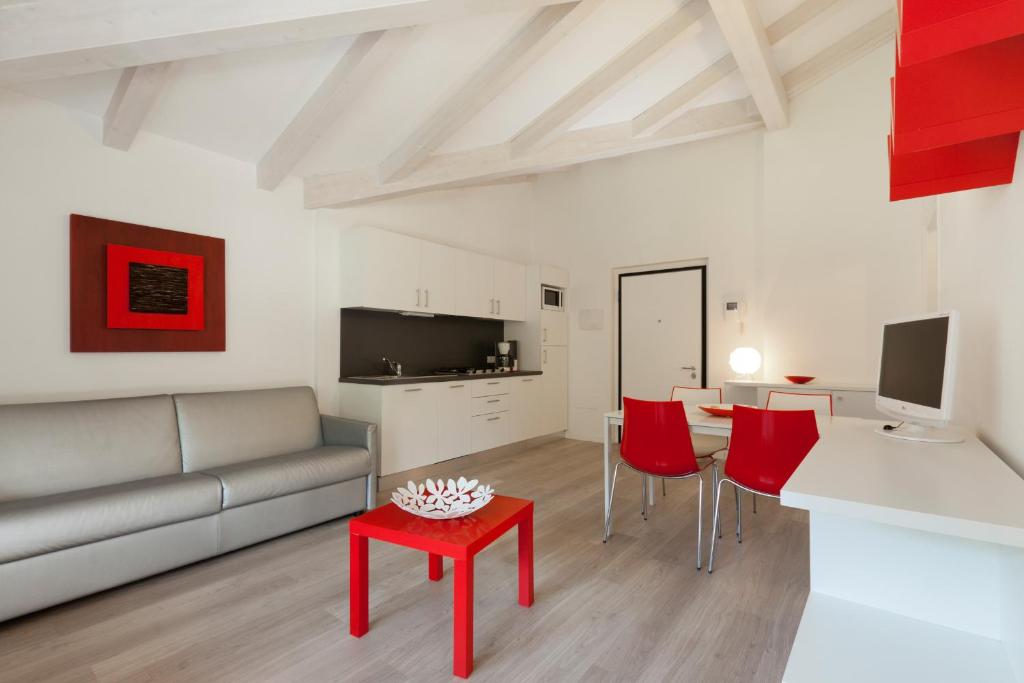 sala de estar con sofá, mesa y sillas rojas en Casa Carla, en Nago-Torbole