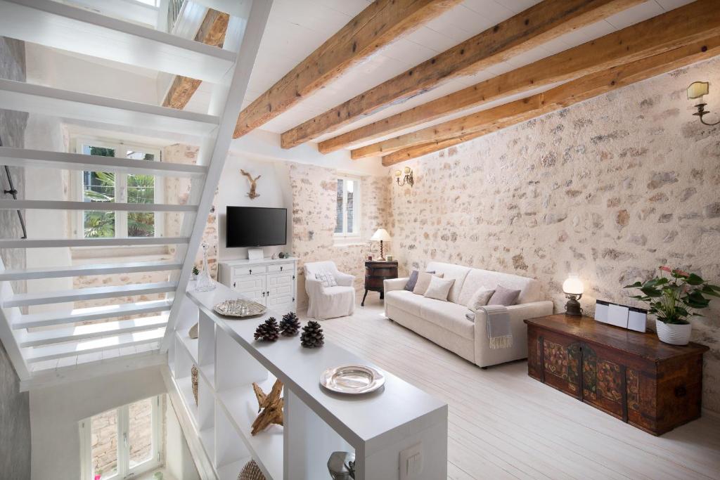 a living room with white furniture and a stone wall at Casa Pharus in Bale