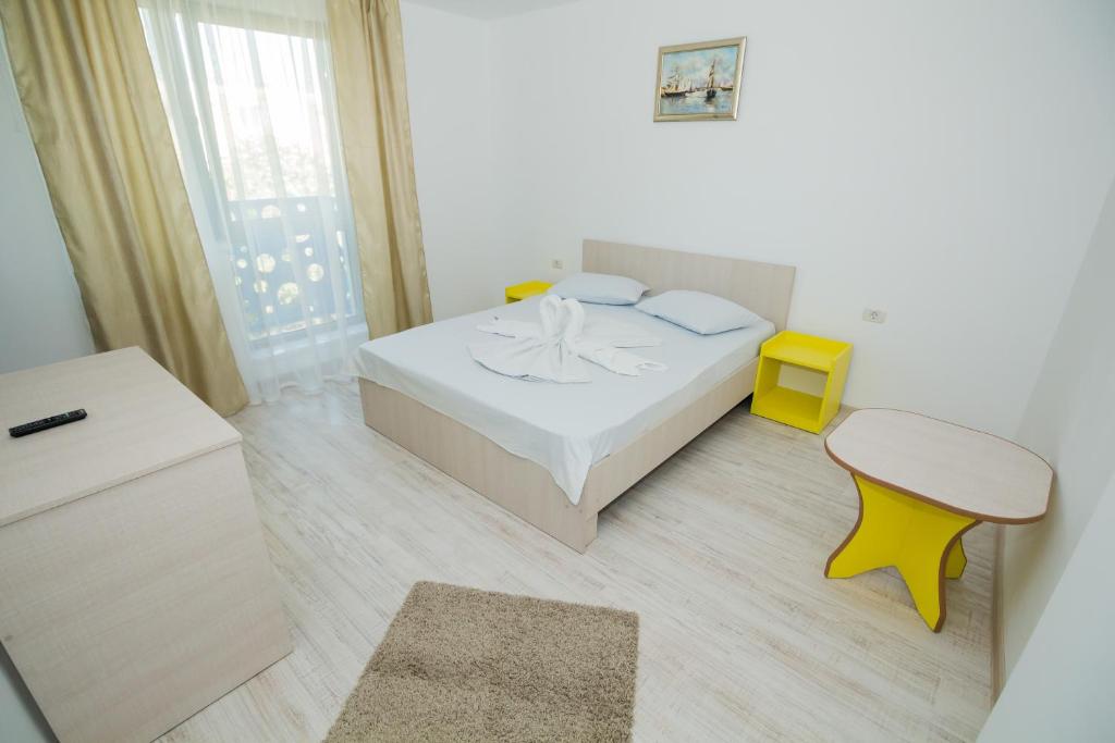 Dormitorio blanco con cama y taburete amarillo en Glam Boutique Hotel, en Eforie Nord