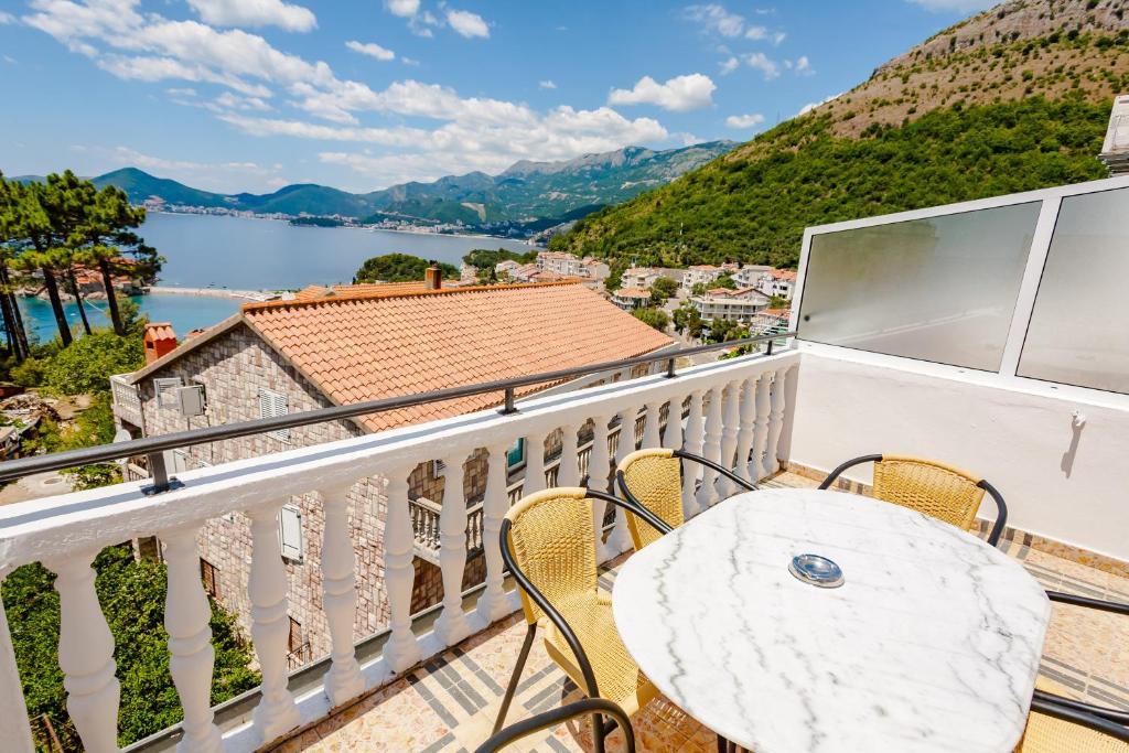 balkon ze stołem i krzesłami oraz widokiem na wodę w obiekcie Apartments Adriatic w miejscowości Sveti Stefan