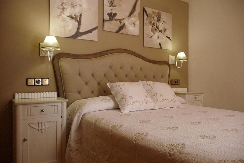 1 dormitorio con 1 cama blanca y 2 lámparas en la pared en Hostal Vidaller en Bielsa