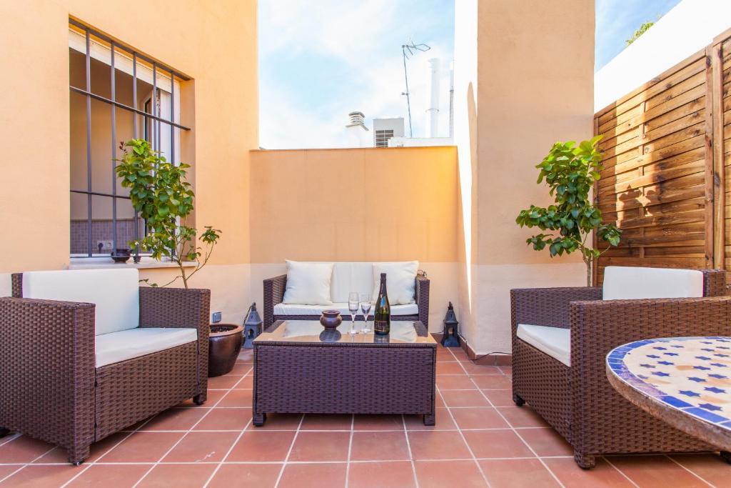 un patio avec des chaises en osier et une table dans l'établissement Bedouin Chic Rooftop - Space Maison Apartments, à Séville
