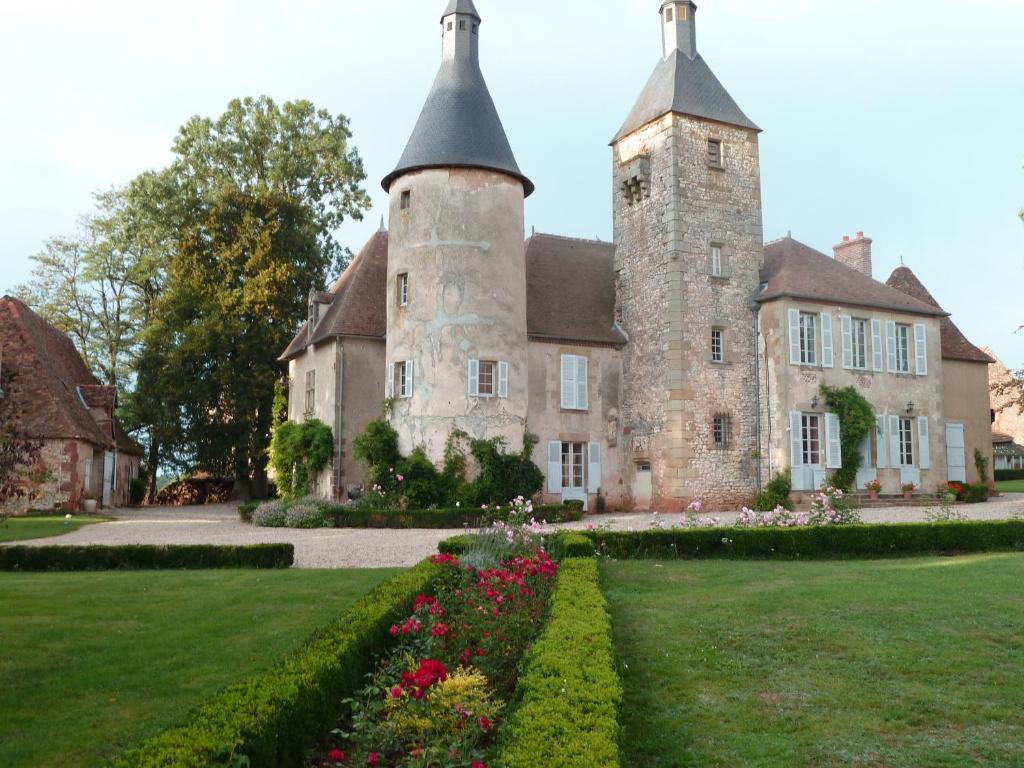 una antigua casa de piedra con una torre y flores en Château de Clusors, en Saint-Menoux