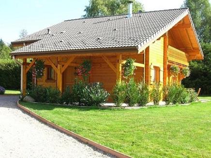 a wooden cabin with a green lawn in front of it at Chalet Les Ecureuils in Saint-Nabord