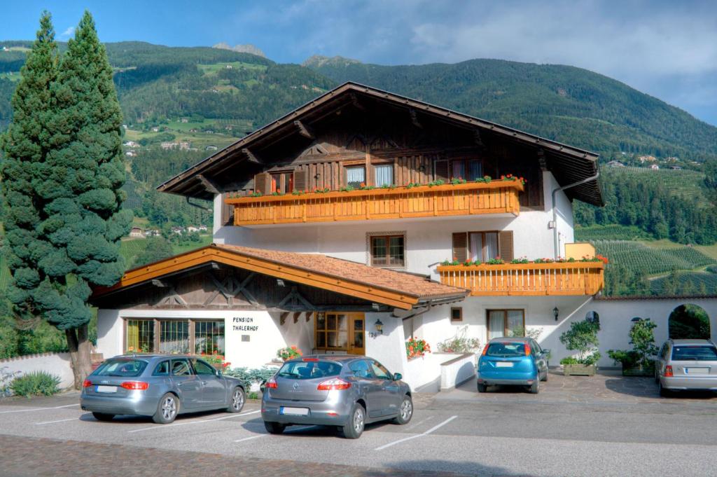 a large building with cars parked in a parking lot at Pension Thalerhof in Rifiano