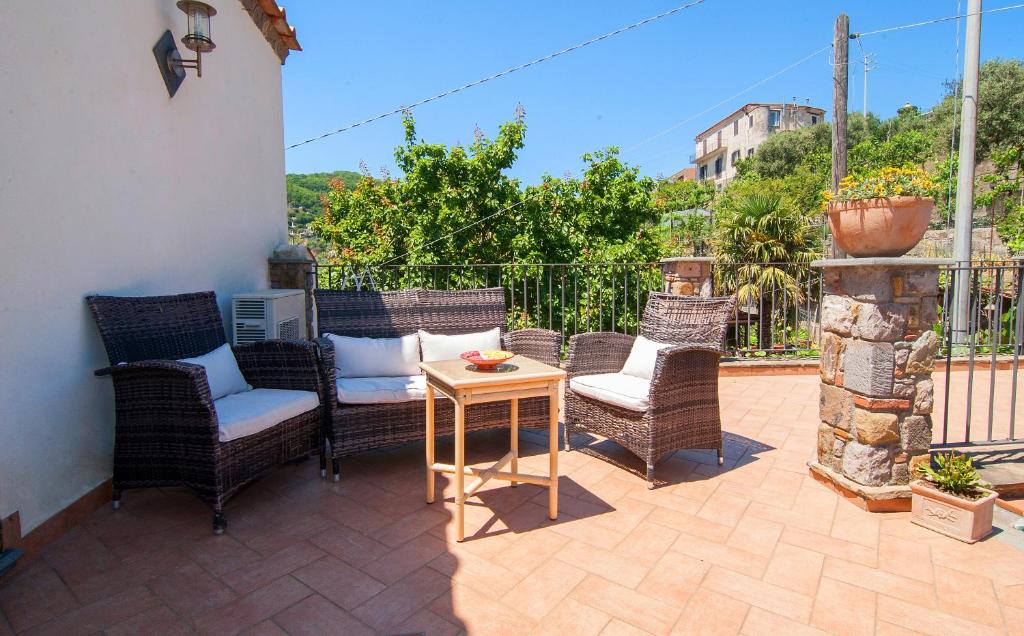 un patio con sillas de mimbre y una mesa de madera. en Casa Vacanze Li Galli en Sant'Agnello