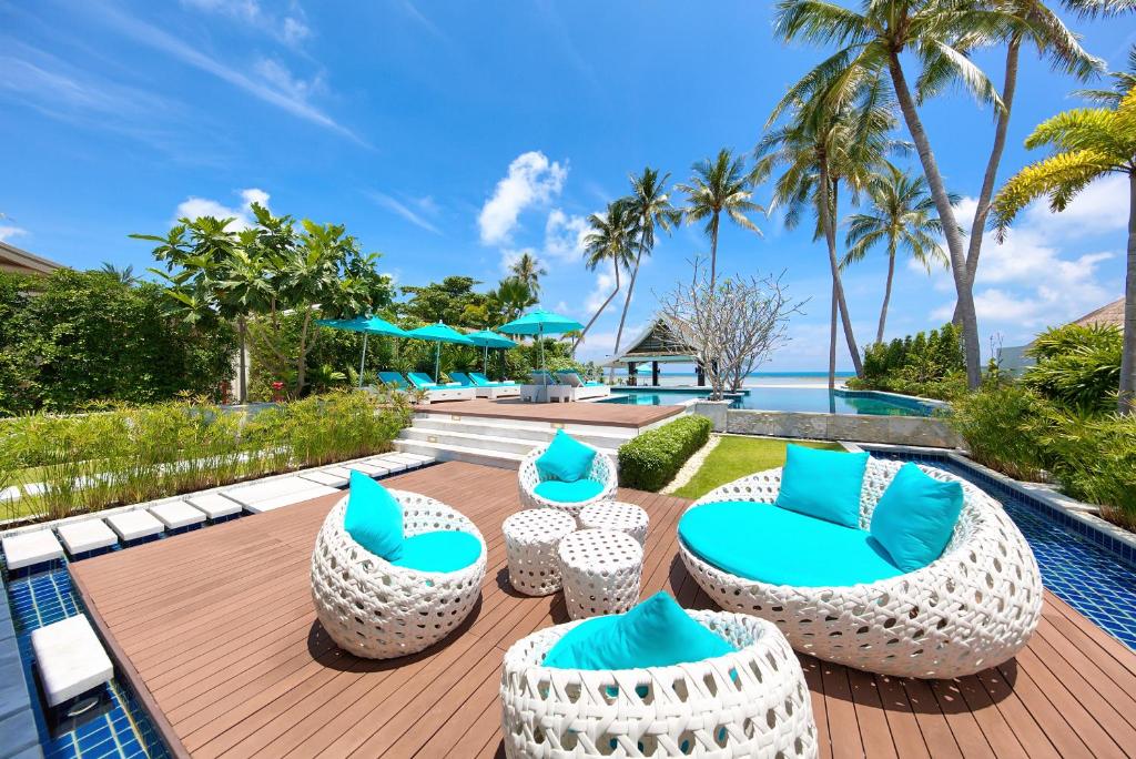 a patio with blue and white chairs and a pool at Beachfront Villa Baan Paradise in Laem Set Beach