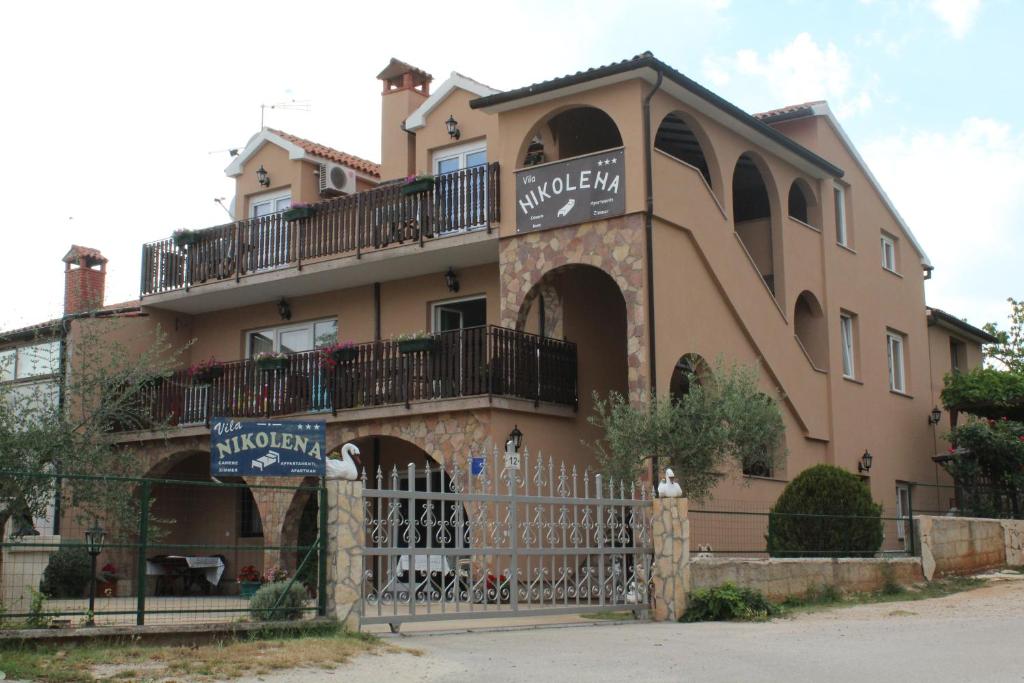 ein großes Haus mit einem Zaun davor in der Unterkunft Apartment Nikolena in Rovinjsko Selo