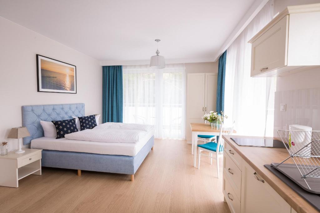 a white bedroom with a bed and a kitchen at Ava Apartamenty in Niechorze