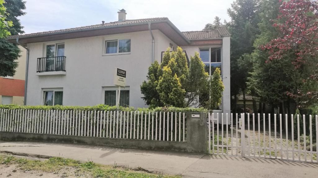 a white house with a fence in front of it at Ilona Apartmanház in Siófok