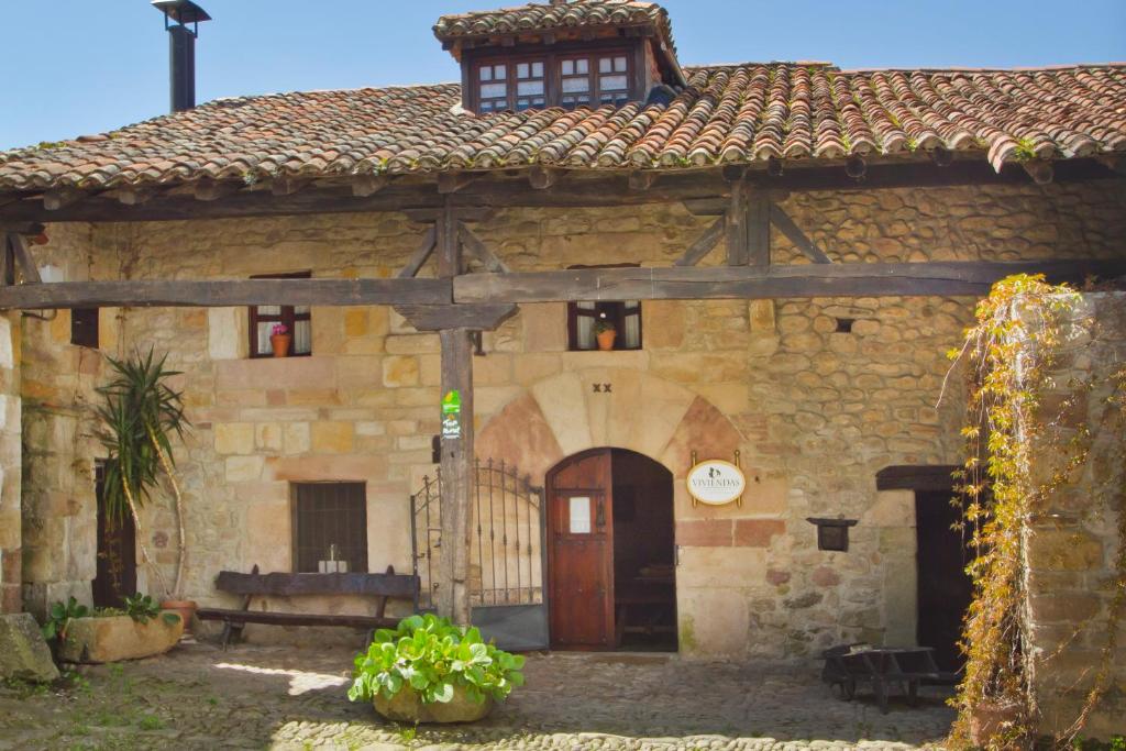 ein altes Steingebäude mit einer roten Tür in der Unterkunft Vivienda rural La Otra Casa in Arenas de Iguña