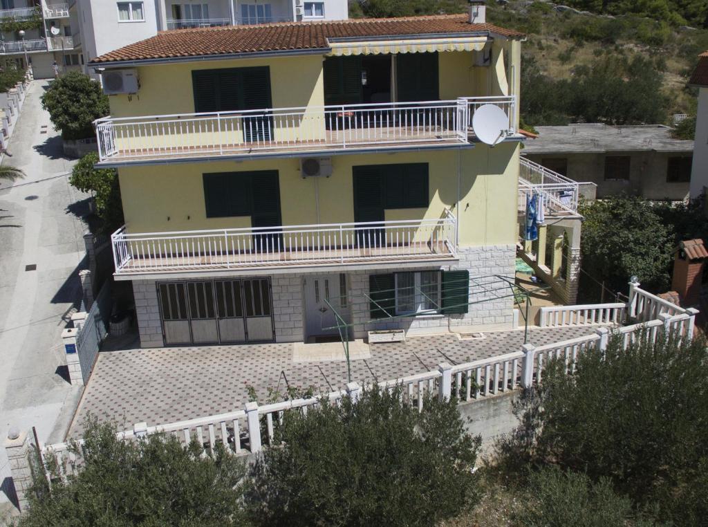 a yellow house with a white fence in front of it at Maglić Apartment in Duće
