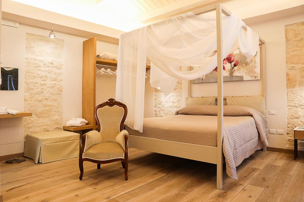 a bedroom with a canopy bed with a chair and a table at B&B Dei Raselli in Guardiagrele