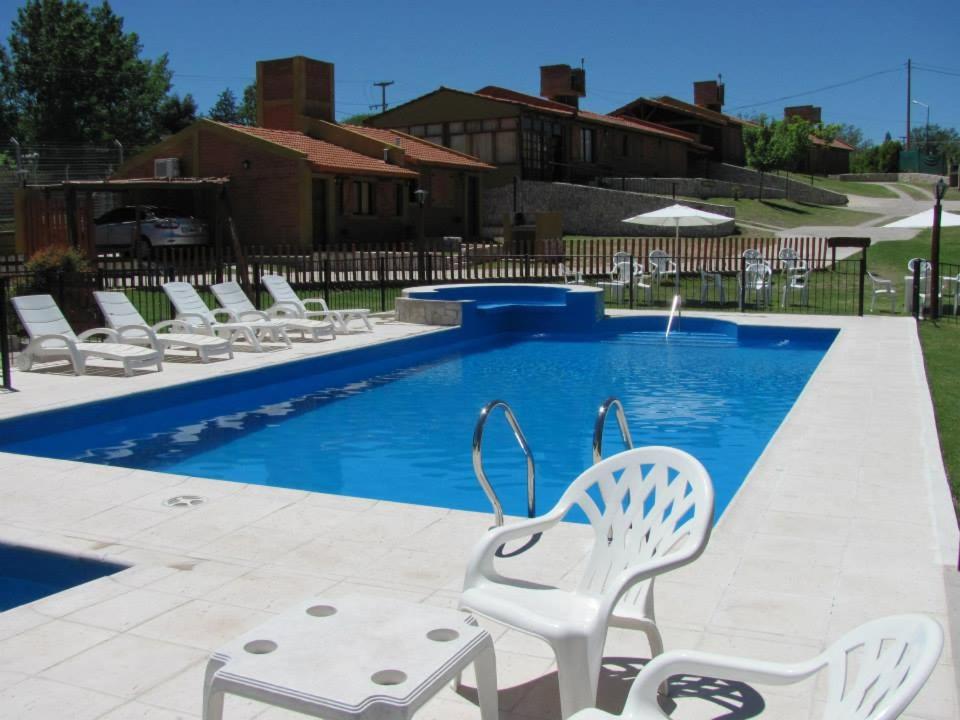 una piscina con sillas blancas y una piscina azul en COMPLEJO DEL MIRADOR con piscina climatizada en Potrero de los Funes