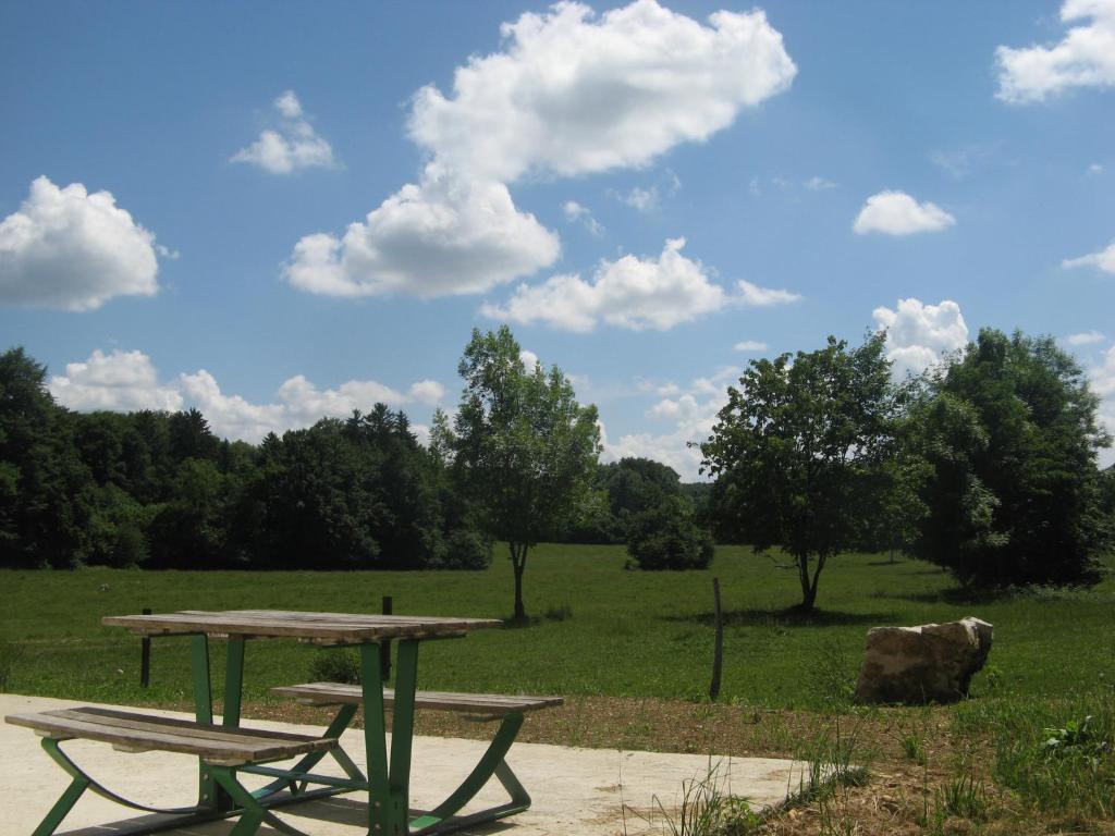 una mesa de picnic y dos bancos en un campo en Gite De La Distillerie, en Arçon