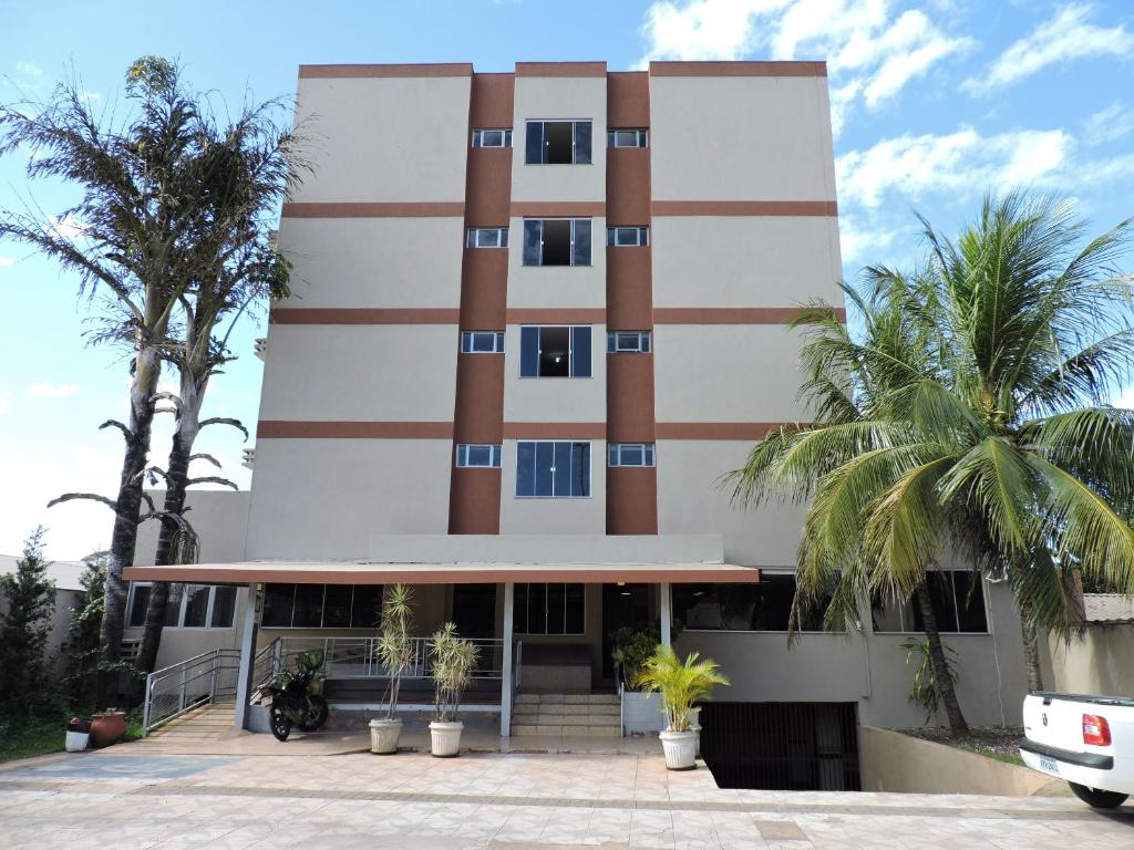 a building with palm trees in front of it at Hotel Galli in Campo Grande