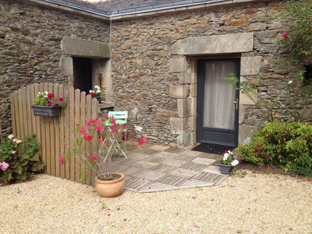 ein Steinhaus mit einem Holzzaun und Blumen in der Unterkunft Gîte la peille in Cordemais