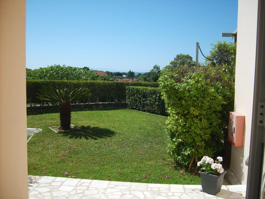 a garden with a hedge and a lawn with flowers at Gouna's Aparts in Xi