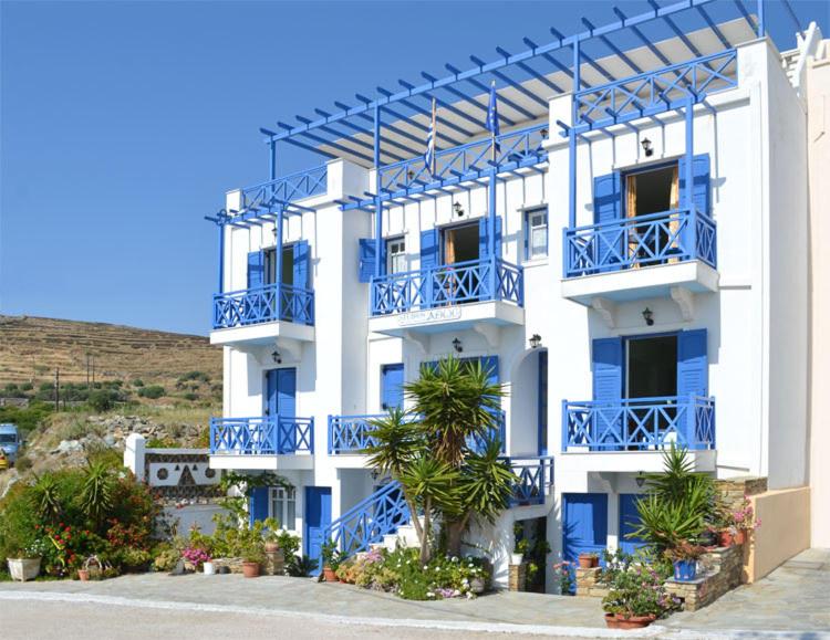 - un bâtiment blanc avec des balcons bleus et des palmiers dans l'établissement Athos Studios, à Tinos