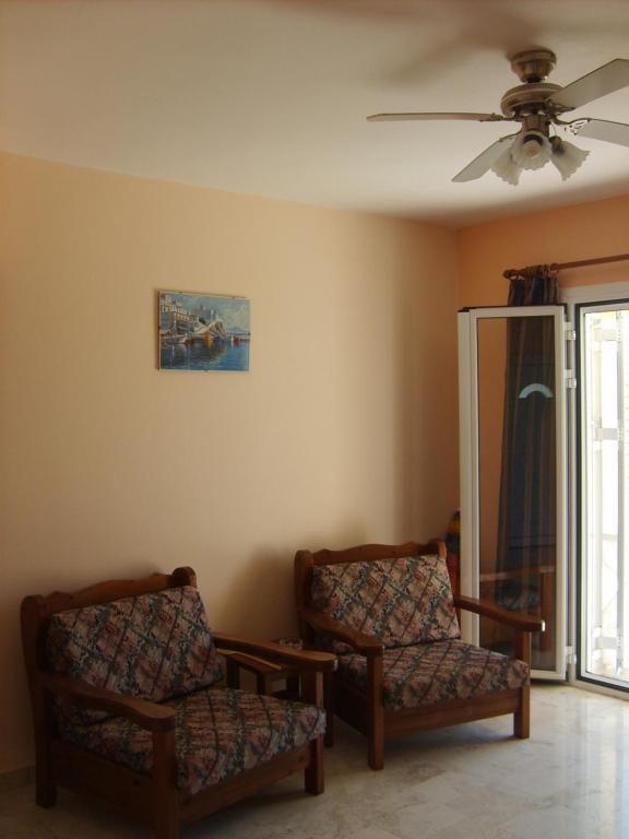 a living room with two chairs and a ceiling fan at Gouna's Aparts in Xi