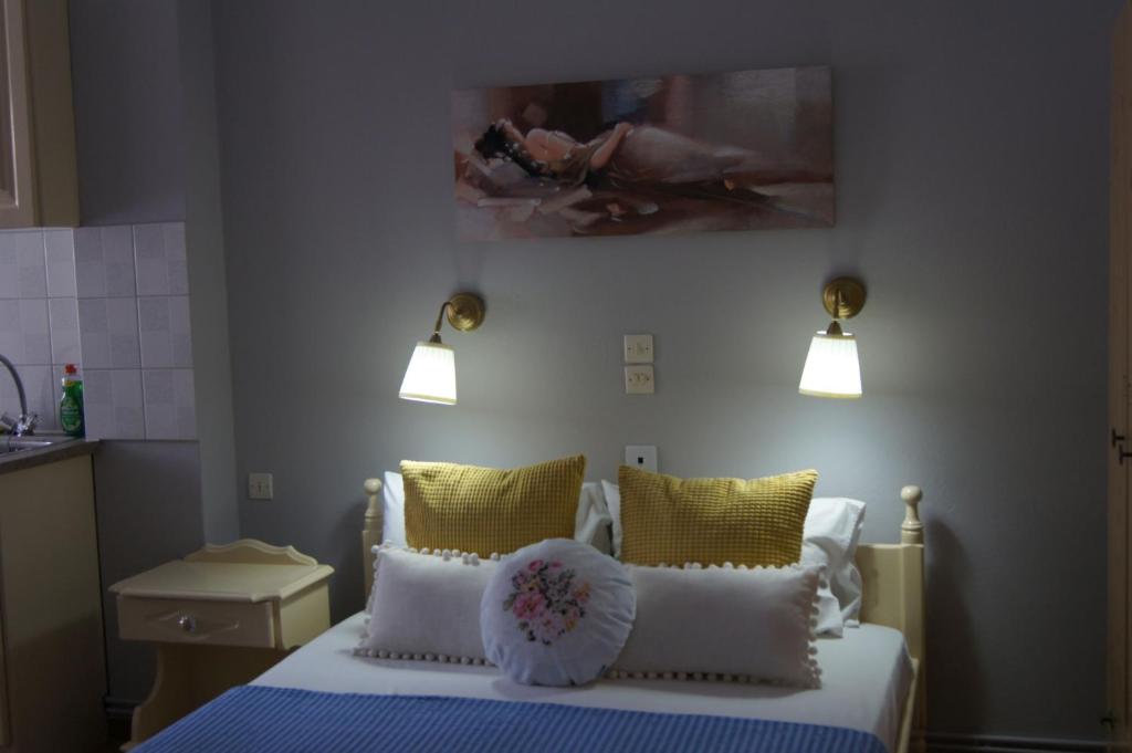 1 dormitorio con 1 cama con almohadas amarillas y 2 luces en Stella Studios, en Patitiri