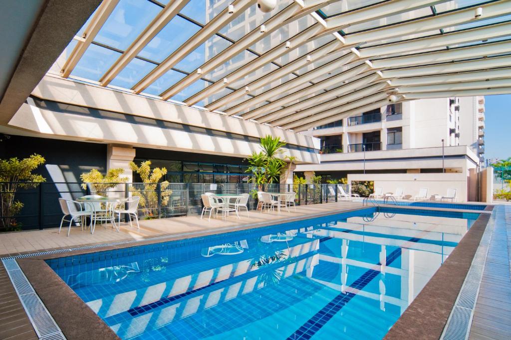 uma piscina com tecto de vidro e um edifício em eSuítes Congonhas by Atlantica em São Paulo