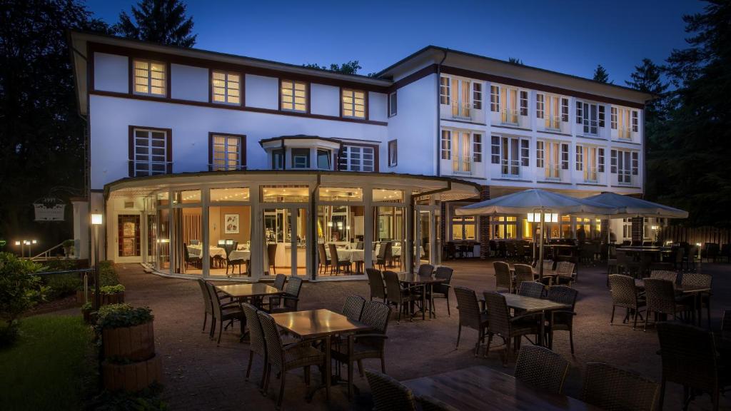 un patio al aire libre con mesas y sillas y un edificio en Hotel Waldhalle, en Mölln