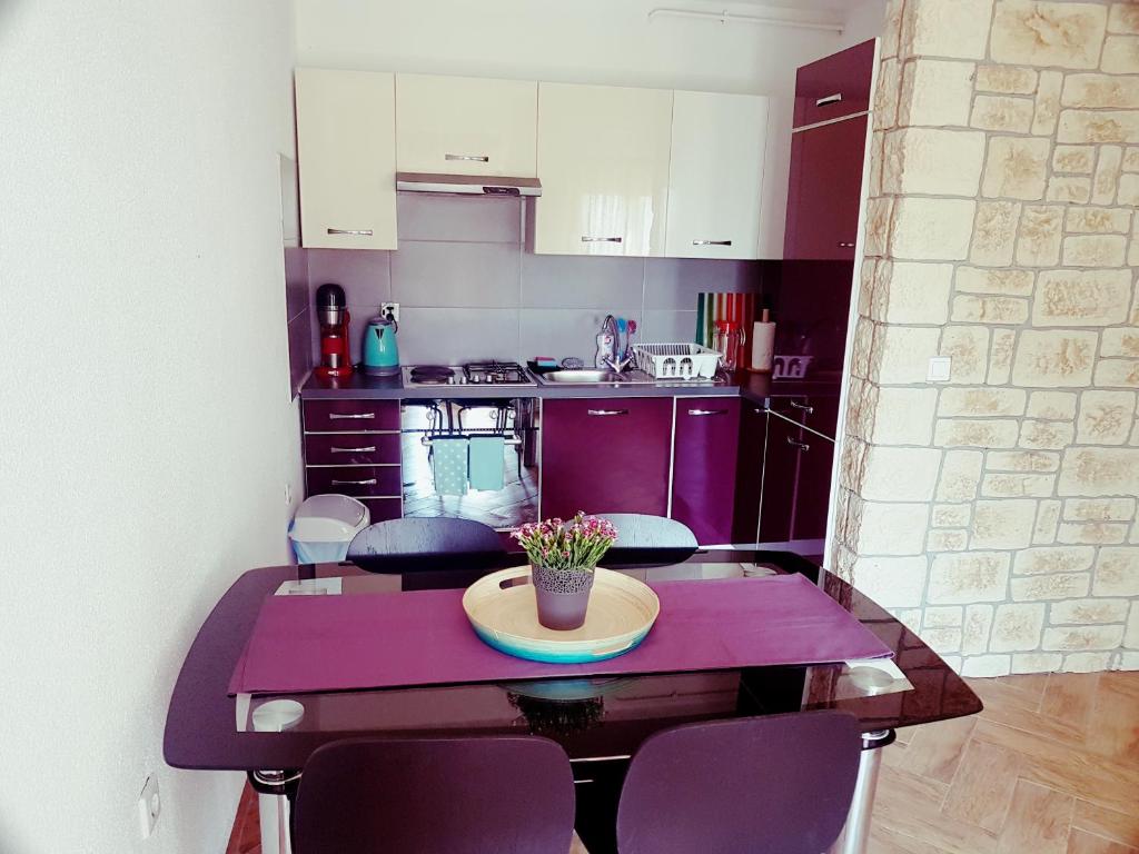 a small kitchen with a table and purple cabinets at DolceFarNiente Fažana in Fažana