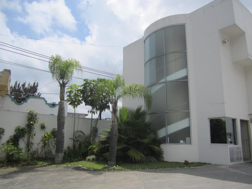 a white building with palm trees in front of it at Auto Hotel Mediterráneo in Xalapa