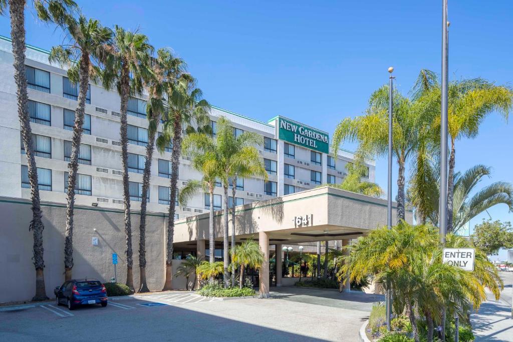 a hotel building with palm trees and a street sign at New Gardena Hotel in Gardena