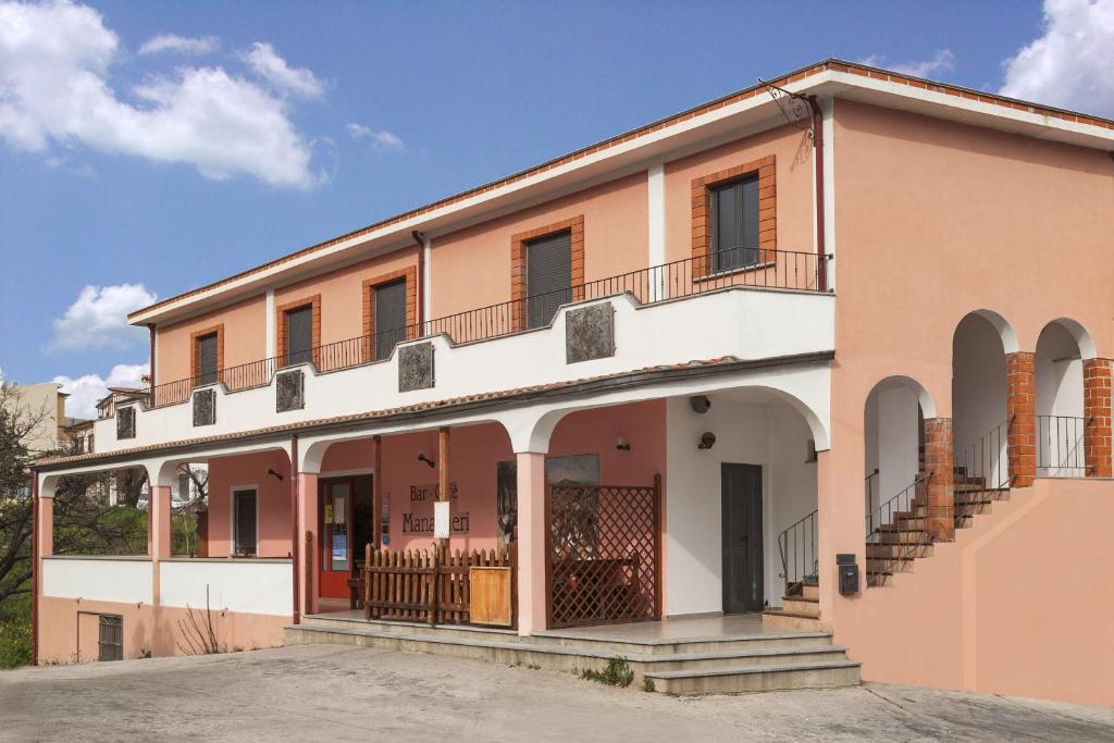 pomarańczowo-biały budynek z balkonem w obiekcie Managheri Wine Bar w mieście Oliena
