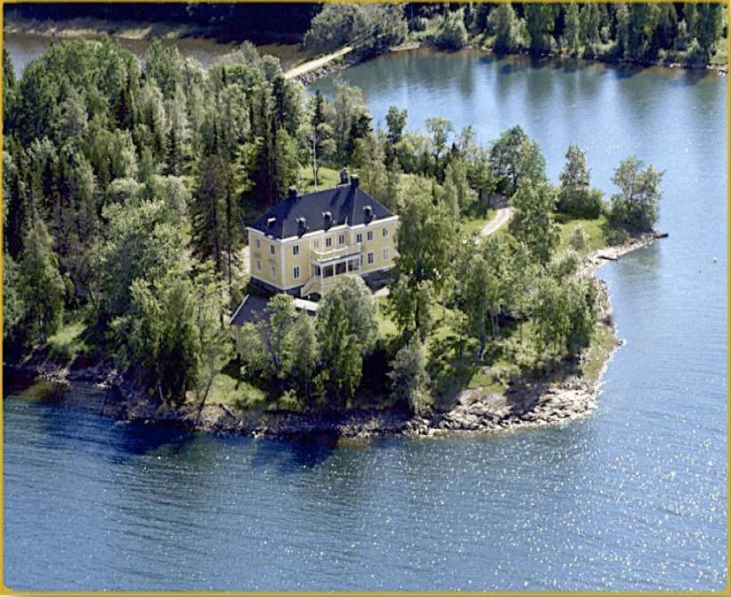 ein großes Haus auf einer Insel im Wasser in der Unterkunft Salsåker Herrgård in Salsåker