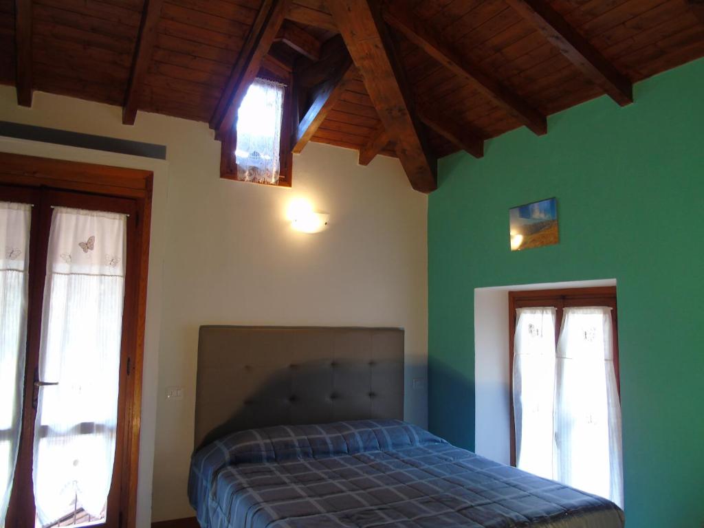 a bedroom with a bed with green walls and windows at Ca' Mea in Baveno