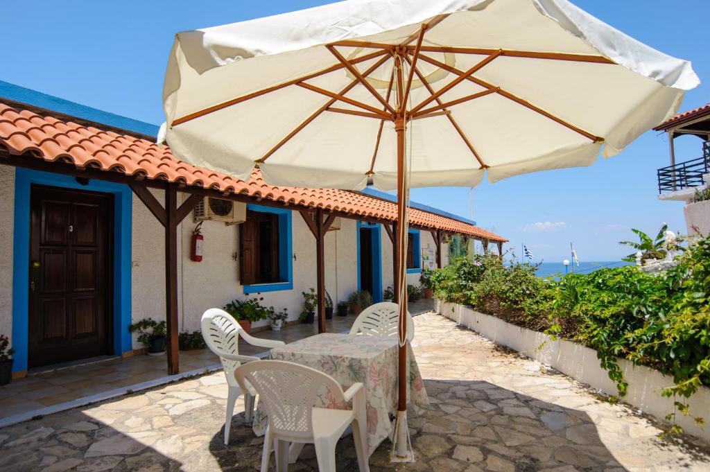 a table and chairs with an umbrella on a patio at Athina Studios in Ágios Dimítrios