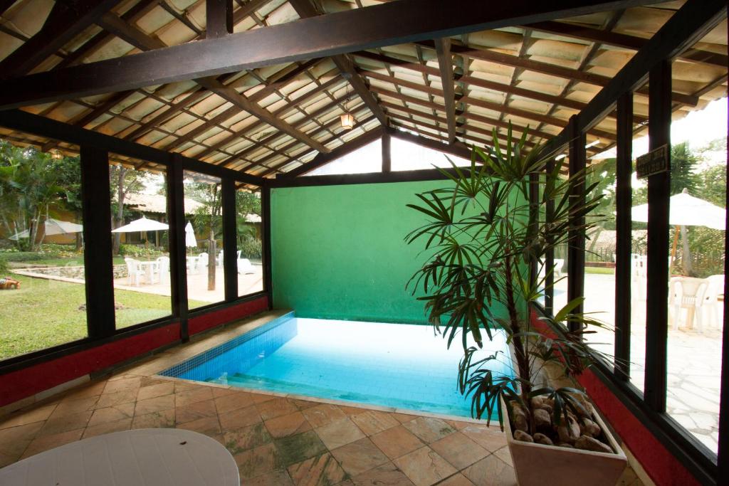 a swimming pool in a pavilion with a plant at Pousada Varandas da Serra in Serra do Cipo