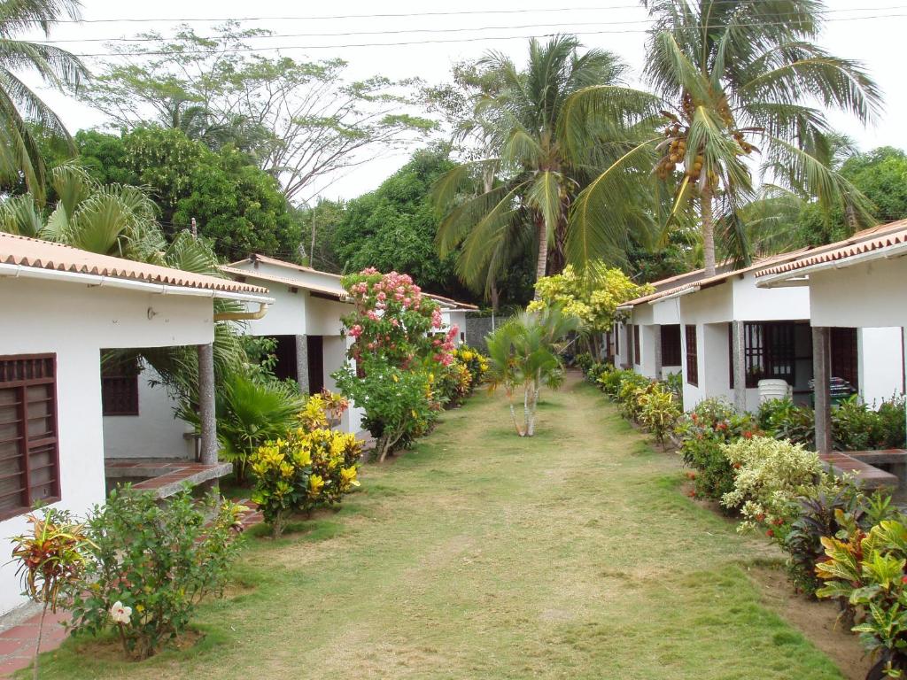 a row of houses with flowers and palm trees at Hostal Roldan in Coveñas
