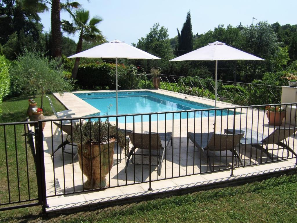 a pool with chairs and umbrellas next to a fence at AU VALLON ROUGE (Studio) in Saint-Paul-de-Vence