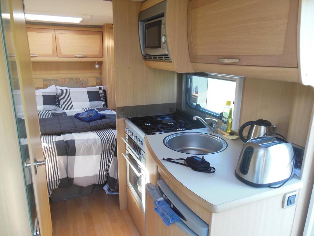 a kitchen with a sink and a stove and a bed at Silverdale Retreat in Orewa